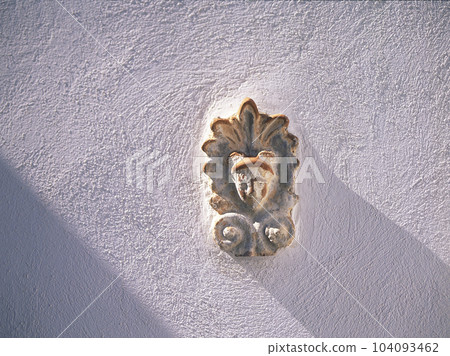 Relief of a face embedded in a Greek white wall Relief of a face embedded in a Greek white wall 104093462