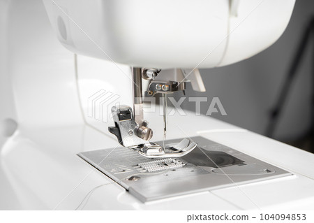Modern white sewing machine presser foot closeup, macro Modern white sewing machine presser foot closeup, macro 104094853