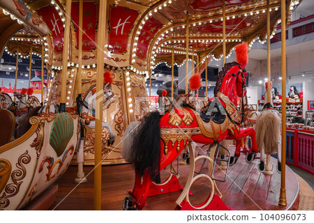 Old French carousel in a holiday park. Three horses and airplane on a traditional fairground vintage carousel. Merry-go-round with horses. Old French carousel in a holiday park. Three horses and airplane on a traditional fairground vintage carousel. Merry-go-round with horses. 104096073