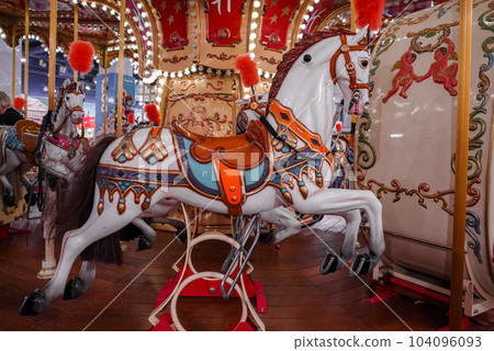 Old French carousel in a holiday park. Three horses and airplane on a traditional fairground vintage carousel. Merry-go-round with horses. 104096093