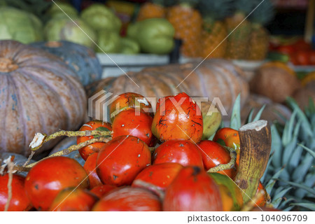 Tropical fresh organic ripe bunch of red pejibayes for sale on stall in market, Healthy peach palm fruit displayed in retail shop of Costa Rica 104096709