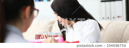 Woman with friend looks into packages after shopping 104096758