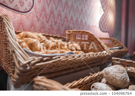 Closeup of freshly made croissants in wicker basket displayed at restaurant in luxurious tourist resort, luxury travel concept for tourists 104096764