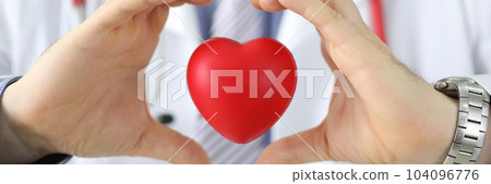 Hands of doctor cardiologist hold red toy heart in air Hands of doctor cardiologist hold red toy heart in air 104096776