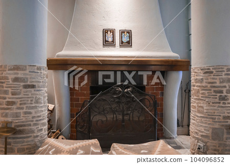 Empty ottomans in front of fireplace between columns in luxurious room at modern hotel, luxury travel concept for tourists 104096852