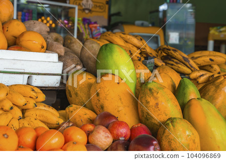 Tropical fresh organic ripe various fruits for sale on stall in local market, Papaya, banana, apple and orange displayed in retail shop 104096869