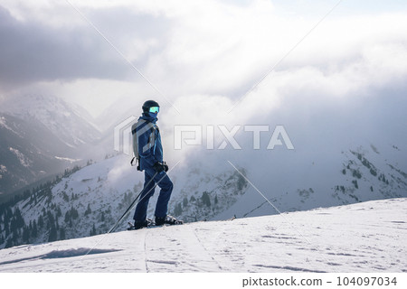 Tourist with ski poles skiing on snow covered mountain with cloudy sky in background during winter vacation, winter holiday travel concept Tourist with ski poles skiing on snow covered mountain with cloudy sky in background during winter vacation, winter holiday travel concept 104097034