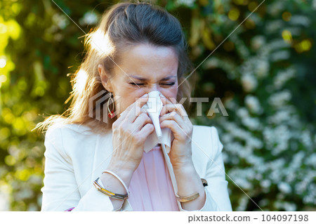 stylish female in dress and jacket in city has allergy attack 104097198