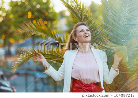 happy elegant woman in pink dress and white jacket in city happy elegant woman in pink dress and white jacket in city 104097212