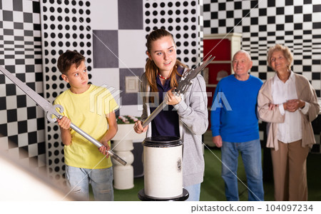 Kids solving conundrum in escape room and grandparents watching them Kids solving conundrum in escape room and grandparents watching them 104097234