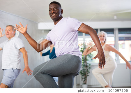 Mature men and women practicing Rock 'n' Roll dance in training hall 104097306