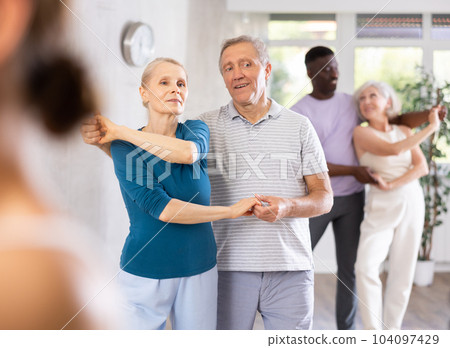 Mature male novice student of fitness studio practices paired Latin American rumba dance Mature male novice student of fitness studio practices paired Latin American rumba dance 104097429