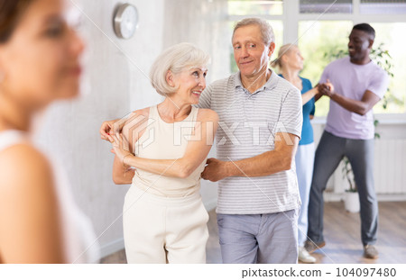 Elderly woman dancing merengue with male partner in latin dance class 104097480