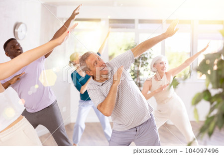 Elderly man performing dabbing during dance class with group Elderly man performing dabbing during dance class with group 104097496