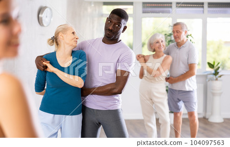 African male novice student of fitness studio practices paired Latin American rumba dance 104097563