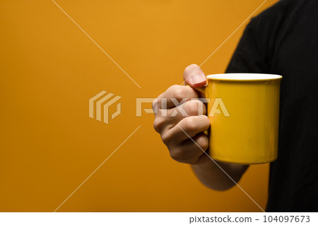 Man holding coffee cup over yellow background. Close up, mockup image, copy space for text 104097673