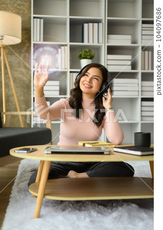 Smiling woman wearing headphone, pressing button on virtual screen. Future technology, innovation and cyberspace Smiling woman wearing headphone, pressing button on virtual screen. Future technology, innovation and cyberspace 104097686