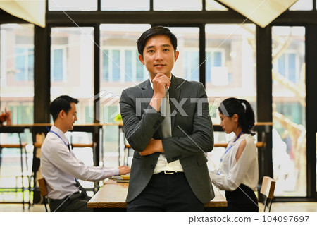 Portrait of asian millennial male executive wearing formal clothes standing and smiling confidently to camera 104097697