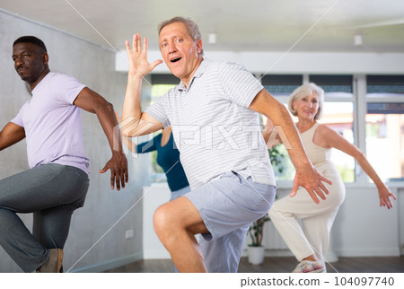 Positive senior man practicing vigorous dance during group class 104097740