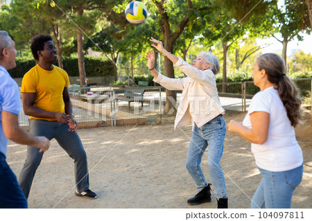 Social club of joyful older diverse people enjoying volleyball on the October sunny day outdoors Social club of joyful older diverse people enjoying volleyball on the October sunny day outdoors 104097811