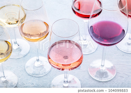 Wine glasses at a tasting. Rose, red, and white wine, drinks on a table 104099883