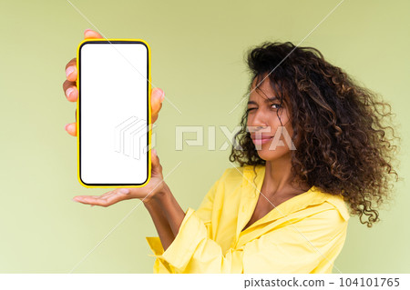 Beautiful african american woman in casual shirt on green background holds a phone with a blank white screen Beautiful african american woman in casual shirt on green background holds a phone with a blank white screen 104101765