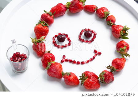 Cheerful emoticon from red berries on the white table. Cheerful emoticon from red berries on the white table. 104101879