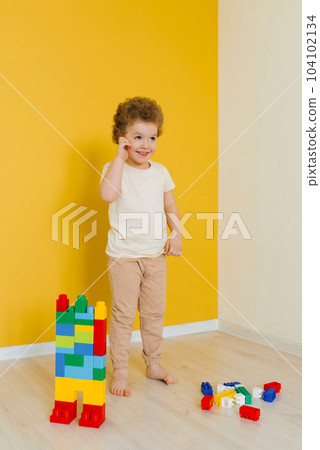 Child is playing with colorful cubes at the table. Kid has fun and builds from bright construction blocks. Early learning. Educational toys 104102134