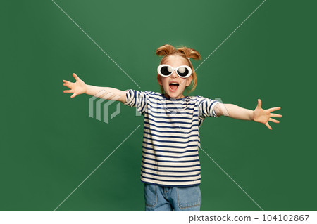 Portrait of emotiona, beautufl little girl, childin striped shirt and sunglasses posing against green studio background Portrait of emotiona, beautufl little girl, childin striped shirt and sunglasses posing against green studio background 104102867