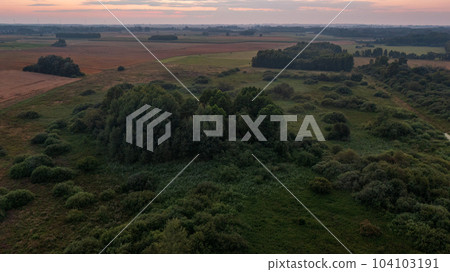 Colorful sunset over forest and fields 104103191