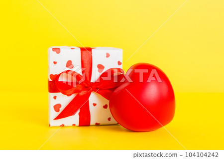 gift box with red bow and red heart on colored background. Perspective view. Flat lay 104104242