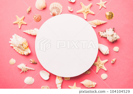 Summer time concept with blank greeting card and blank white paper on colored background. Seashells from ocean shore in the shape of frame separated with space for text top view 104104529
