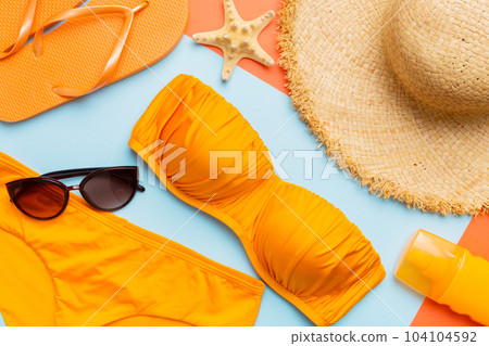 Woman swimwear and beach accessories flat lay top view on colored background Summer travel concept. bikini swimsuit, straw hat and seasheels. Copy space Top view Woman swimwear and beach accessories flat lay top view on colored background Summer travel concept. bikini swimsuit, straw hat and seasheels. Copy space Top view 104104592