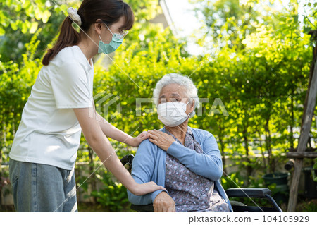 caregiver help and care Asian senior woman patient wearing mask sitting on wheelchair at nursing hospital ward, healthy strong medical concept. 104105929