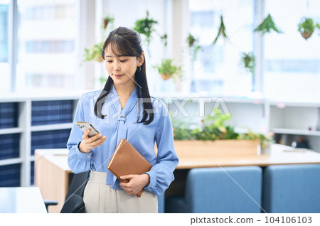 在辦公室操作智能手機的商務休閒年輕女性 在辦公室操作智能手機的商務休閒年輕女性 104106103