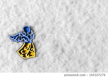blue and yellow toy angel on white snow 104107278