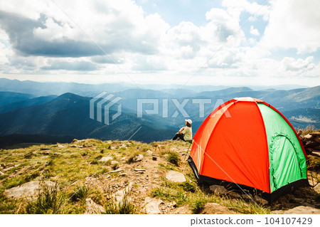 Woman with a tent on top of a mountain Woman with a tent on top of a mountain 104107429