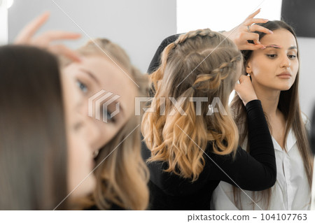 This photo conveys the atmosphere of a beauty salon, where the makeup artist improves the shape of the client's eyebrows. Each movement of the master is aimed at creating the perfect frame for the 104107763