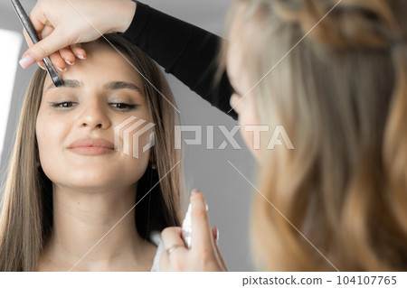 Eebrow correction when the makeup artist with great attention develops shape fits perfectly into features client face adding uniqueness and beauty. Drawing and eyebrow in beauty salon by cosmetologist 104107765
