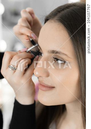 Magical moment makeup artist carefully corrects eyebrows improving look face beautiful woman. Each movement master is professional and fussily working to create perfect eyebrow shape in beauty salon Magical moment makeup artist carefully corrects eyebrows improving look face beautiful woman. Each movement master is professional and fussily working to create perfect eyebrow shape in beauty salon 104107767