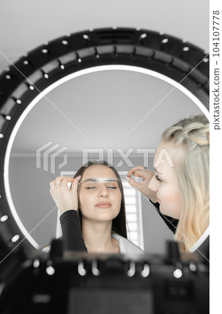 Look at this fascinating photo conveys eyebrow correction process to a beautician. Eyebrow designer with deft movements gives symmetry and harmony to eyebrows, giving the woman's face sophistication. Look at this fascinating photo conveys eyebrow correction process to a beautician. Eyebrow designer with deft movements gives symmetry and harmony to eyebrows, giving the woman's face sophistication. 104107778