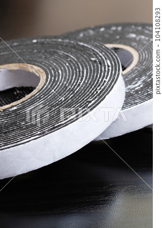 Three reels of double-sided tape on wooden table 104108293