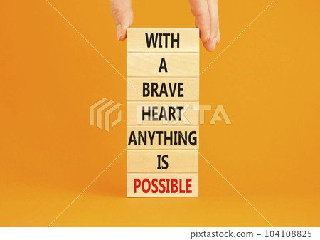 Possible symbol. Concept words With a brave heart anything is possible on wooden blocks on a beautiful orange table orange background. Business motivational brave heart possible concept. Copy space Possible symbol. Concept words With a brave heart anything is possible on wooden blocks on a beautiful orange table orange background. Business motivational brave heart possible concept. Copy space 104108825