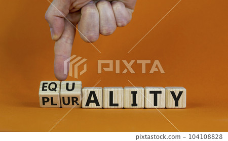 Equality or plurality symbol. Hand turns cubes and changes the word 'plurality' to 'equality'. Beautiful orange background. Business and plurality or equality concept. Copy space. Equality or plurality symbol. Hand turns cubes and changes the word 'plurality' to 'equality'. Beautiful orange background. Business and plurality or equality concept. Copy space. 104108828