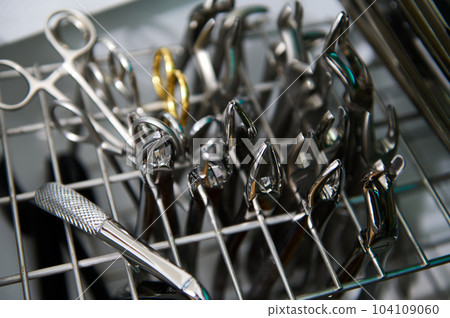 Selective focus on stainless steel professional dental extraction forceps and various medical instruments, being sterilized under UV inside an autoclave or ultraviolet sterilizing machine, thermostat Selective focus on stainless steel professional dental extraction forceps and various medical instruments, being sterilized under UV inside an autoclave or ultraviolet sterilizing machine, thermostat 104109060