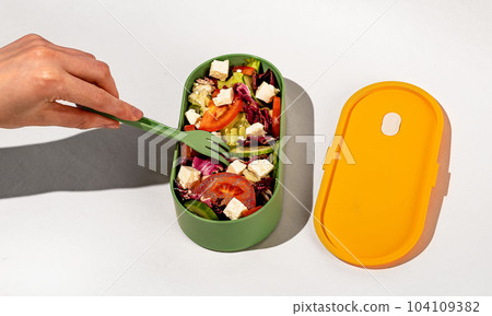Eating vegetarian salad from lunch box Eating vegetarian salad from lunch box 104109382