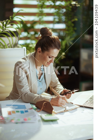 happy woman employee in light business suit in green office 104109439