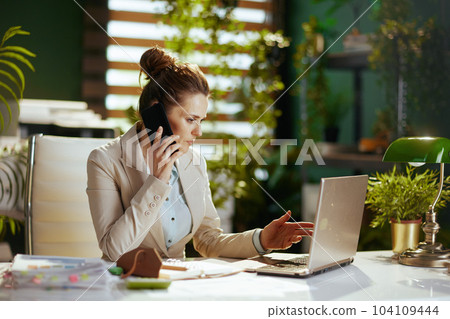 business owner woman in green office talking on phone business owner woman in green office talking on phone 104109444