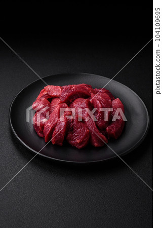 Juicy raw beef with spices, salt and herbs on a dark concrete background 104109695