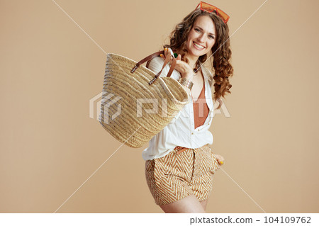 smiling trendy female in blouse and shorts isolated on beige 104109762